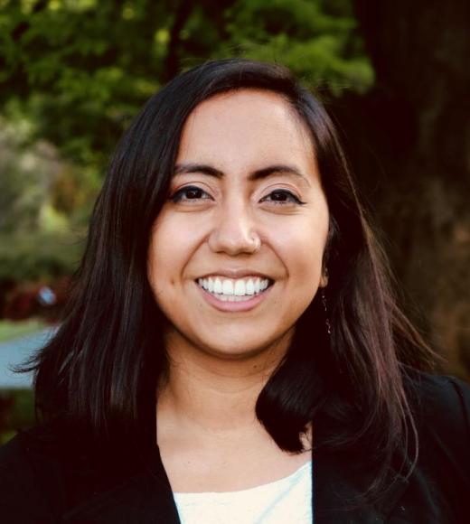 Portrait of Deniss Martinez standing in front of a tree wearing a black blazer